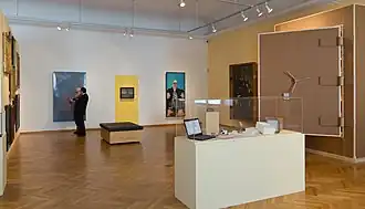 Vitrine im Vordergrund: Laptop mit Archivsoftware, Digitalkamera, Verpackungsmaterial