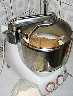 Haushalts­knet­maschine mit rotierender Schüssel beim Kneten von Brotteig