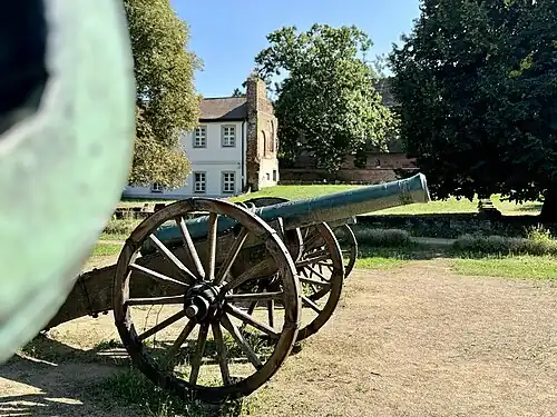Zu sehen ist im Vordergrund eine von vier Kanonen aus dem deutsch-französischen Krieg von 1870. Im Hintergrund ein Teil des Anbaus am Bismarck'schen Wohnsitz sowie Grundriss des einstigen Wohnhauses der Familie.