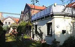 Hinterhof mit ehemaligen Gewerbebauten aus Backstein. Im gepflasterten Boden sind Reste von Gleise erkennbar. Über dem Hof quer zwei Stahlträger mit Resten einer Krananlage