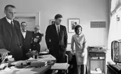 Präsident Kennedy (Mitte), seine Frau Jacqueline (rechts), Vizepräsident Johnson (links) sowie Arthur Schlesinger und Arleigh Burke beobachten den Flug im Fernsehen