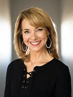 Kim Rhodenbaugh trägt auf diesem Farbfoto eine schwarze Bluse und große Ohrringe.