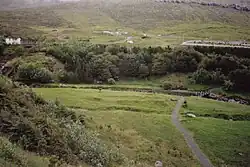 Wald am Rande von Klaksvík. Auf der Wiese die Fundamente eines ovalen Gebäudes aus der Wikingerzeit