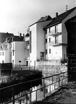 Dieselbe Mühlbachstelle, rund zehn Jahre später, um 1960. Mit moderneren Geschäftshäusern, aber noch unverrohrt