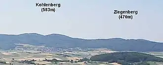 Der Kohlenberg und sein nordöstlicher Nachbar Ziegenberg (470 m) vom Christenberg (387,4 m) im Burgwald aus; im Vordergrund die Wetschaft-Senke mit dem 324 m hohen, bewaldeten Kainsberg bei Münchhausen-Wollmar.