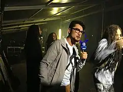 Moderator mit ARD-Mikrofon interviewt die Band Korn neben der Bühne