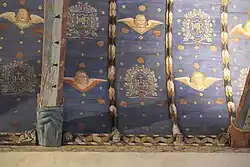 Bemalte Holzdecke mit skulptiertem Balkenende