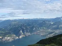 Blick vom Gipfel auf das Nordufer des Gardasees, im Hintergrund die schneebedeckten Adamello-Presanella-Alpen