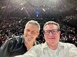 Man sieht die beiden Moderatoren (rechts Ulf Buermeyer, links Philip Banse) wie sie ein Selfie mit dem Publikum machen bei der Lage Live in München