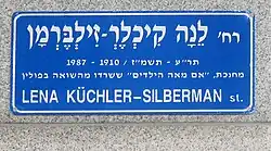 blaues Straßenschild mit dem Namen Küchler-Silbermans und einer Inschrift auf Hebräisch