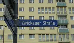 blaues Schild mit dem Straßennamen vor einem Hochhaus