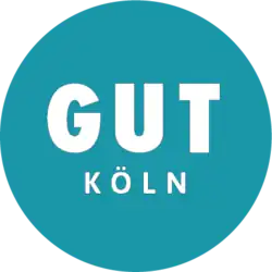 Einfarbiger Kreis in Türkis. In der Mitte steht groß in weißen Großbuchstaben „GUT“, darunter etwas kleiner, aber ebenfalls in weißen Großbuchstaben „Köln“