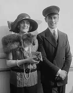 Edwina und Louis Mountbatten sind nebeneinander stehend fotografiert. Die Fotografie ist in schwarz-weiß. Edwina M. trägt einen großen Hut und trägt einen Pelzschal. Sie hält eine kleine Tasche. Louis M. trägt einen Hut und einen Anzug.