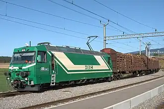 Ge 4/4 22 und zwei mit Holz be­ladende Güterwagen in Apples