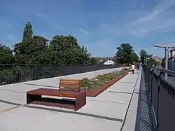 Aus Asphaltplatten zusammengesetzter Boden, in der Mitte sind Blumenbeete etwas über Bodenhöhe eingebaut