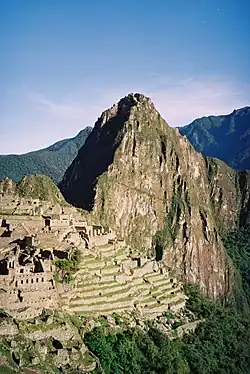 Der Huayna Picchu ragt im Hintergrund der Ruinen von Machu Picchu auf