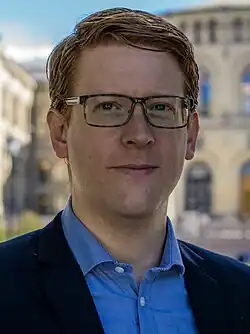 Foto eines Manns mit Brille, im Hintergrund ist das norwegische Parlamentsgebäude zu erkennen