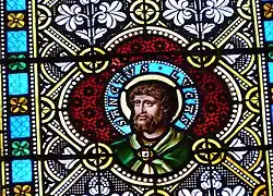 Detail eines Glasfensters im Kirchenschiff mit dem Apostel Lukas