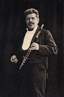 Flötist und Flötenbauer von vorn stehend in schwarzweiß mit Flöte in der Hand.