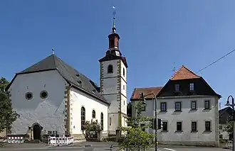 Evang. Kirche von Meddersheim (mit Baustilen von Romanik bis Barock), rechts das ehemalige Lehrerwohnhaus von 1737.