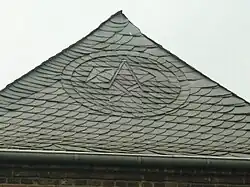 Zunftzeichen der Dachdecker als Verzierung in einem Schieferdach