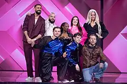 Foto von acht Personen, die für ein Gruppenfoto auf einer Bühne stehen