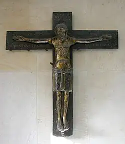 Das Mindener Bronzekreuz (1070/1120): Christus ist zwar mit geöffneten Augen, eher stehend als hängend, ohne Seitenwunde, dennoch mit leichten Anzeichen des Leidens, eingesunkener Brust und heruntergezogenen Mundwinkeln dargestellt.