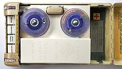 Innenansicht des mit Bedientasten (links), Spulen für den Tondraht (blau), Tonkopf für Draht (oben, zwischen den Spulen) und Batteriefach (rechts, ohne Batterie)