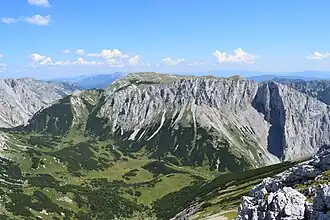 Blick vom Fölzkogel nach Osten über die Fölzalm auf die Westseite der Mitteralm. Rechts mit Schlagschatten markant vorspringend die Schartenspitze (1747&nbsp;m), darüber der Kleine Winkelkogel (1918&nbsp;m) unmittelbar links davon der Große Winkelkogel (1957&nbsp;m). Nach links hinten steigt das Plateau zum Kampl (1990&nbsp;m) an.