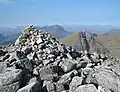 Der Gipfelcairn des Mullach Coire Mhic Fhearchair, rechts im Hintergrund der Beinn Tarsuinn