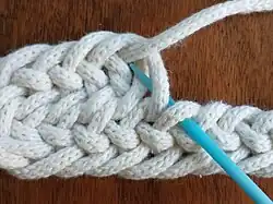 Schritt 1: F1 = 1 Schlinge von vorn; UO = 1 unter, 1 über (anschließend Nadel durchziehen)