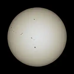 Terrestrische Aufnahme von verschiedenen gleichzeitig aufgetretenen Sonnenflecken im sichtbaren Lichtspektrum auf der vollständig abgebildeten Sonnenscheibe