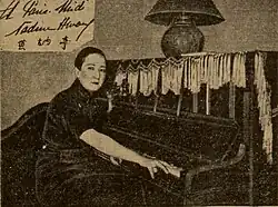 Nadine Hwang ist sitzend an einem Klavier zu sehen. Sie schaut in die Kamera und trägt kurzes Haar. Die Fotografie ist in Sepia.