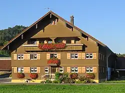 zweigeschossiger, verschindelter Bau mit aufgesteiltem Satteldach