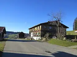 zweigeschossiger, verschindelter Blockbau mit Flachsatteldach und Längsschopf