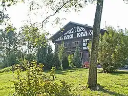 zweigeschossiger, teils verbretterter Blockbau mit Flachsatteldach, Fachwerkteil und -giebel