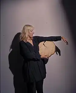 Schottische Künstlerin Katie Paterson posiert für eine Porträtfotografie mit einem abgesägten Baumstamm.