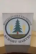 Ortswappen von Kurort Hartha seit 1927 mit dem aktuellen Markennamen über dem Eingang zum ehem. Gemeindeamt, jetzt Uhrentechnische Lehrschau Hennig