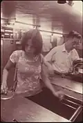 Zwei Fahrgäste der New York City Subway werfen Zahlmarken in eine Bahnsteigsperre ein, 1974