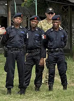 Polizisten bei der Ausbildung durch australische Soldaten und Polizeiabzeichen unter der UN-Verwaltung 2001