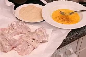 Panieren von (bereits mehlierten) „Seelachs­filets“ mit geschla­genem Ei und Panier­mehl