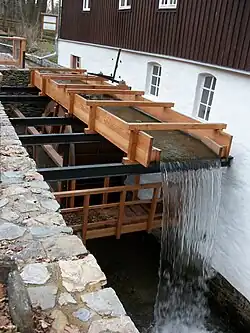 Die Gebäuderückseite mit Wasserbett und oberschlächtigem Wasserrad, 2018 erneuert.