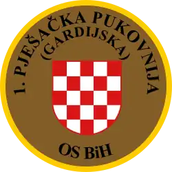 Soldat des 1.&nbsp;Infanterie-(Garde-)Regiments OS&nbsp;BiH (Traditionsregiment HVO) mit seinem Partner von der US-Armee während eines Manövers auf dem Truppenübungsplatz „Eugen Kvaternik“ (2012) und Ärmelabzeichen der Einheit.