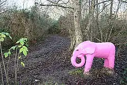 Dieses Farbfoto zeigt einen pinken Elefanten als Symbolbild und wurde 2008 im englischen Freizeitpark Whin Park neben einer Kinderbahn aufgenommen.