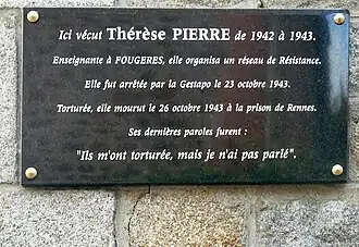 Hier ist die Gedenktafel am ehemaligen Wohnhaus wo Pierre lebte zu sehen. Die Tafel ist aus schwarzem Stein und nimmt das gesamte Bild ein. Die Mauer dahinter ist Naturstein. Mit weißer kursiv verlaufender Schrift ist folgendes graviert:„Ici vécut Thérèse Pierre de 1942 à 1943. Enseignante à Fougères, elle organisa un réseau de résistance. Elle fut arrêtée par la Gestapo le 23 octobre 1943. Torturée, elle mourut le 26 octobre 1943 à la prison de Rennes. Ses dernières paroles furent : "Ils m’ont torturée, mais je n’ai pas parlé.“ Übersetzung: „Thérèse Pierre lebte hier von 1942 bis 1943. Sie war Lehrerin in Fougères und organisierte ein Widerstandsnetz. Am 23. Oktober 1943 wurde sie von der Gestapo verhaftet. Sie wurde gefoltert und starb am 26. Oktober 1943 im Gefängnis von Rennes. Ihre letzten Worte waren: "Sie haben mich gefoltert, aber ich habe nicht geredet.“