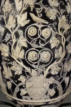 Seite mit der Frauen- und der Silenmaske. Letztere mit den sichtbaren Bruchstellen