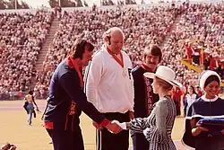 Robin Tait mit Goldmedaille bei den Commonwealth Games 1974, Prinzessin Anne, in blauem Sommerkleid und mit Hut, gratuliert den Diskus-Siegern auf dem Treppchen