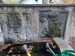 Wappen auf dem Reformierten Friedhof mit einem Wappen mit Freiherrenkrone (7 Zacken) umrandet von einem Löwen und einem Steinbock (Inhalt Brandis Fackel?) sowie Wappen der Rosenroll und Jecklin links