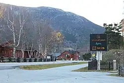 Foto einer von Holzhäusern gesäumten Straße mit einer elektronischen Verkehrsanzeige