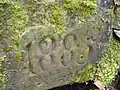 Bogenstein, weitgehend vergraben, Jahreszahl 1885